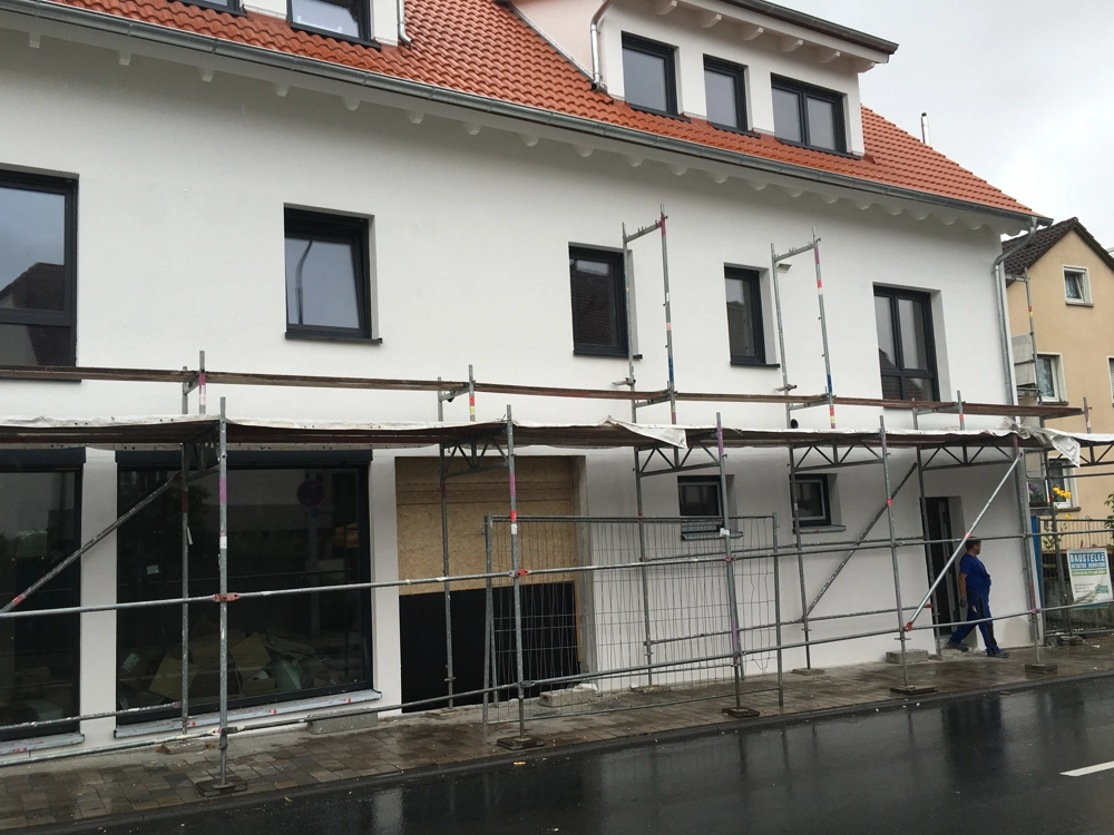 Gerüst vor frisch verputzter Gebäudeaußenwand eines Wohngebäudes – Fassadenbau mit Putzarbeiten