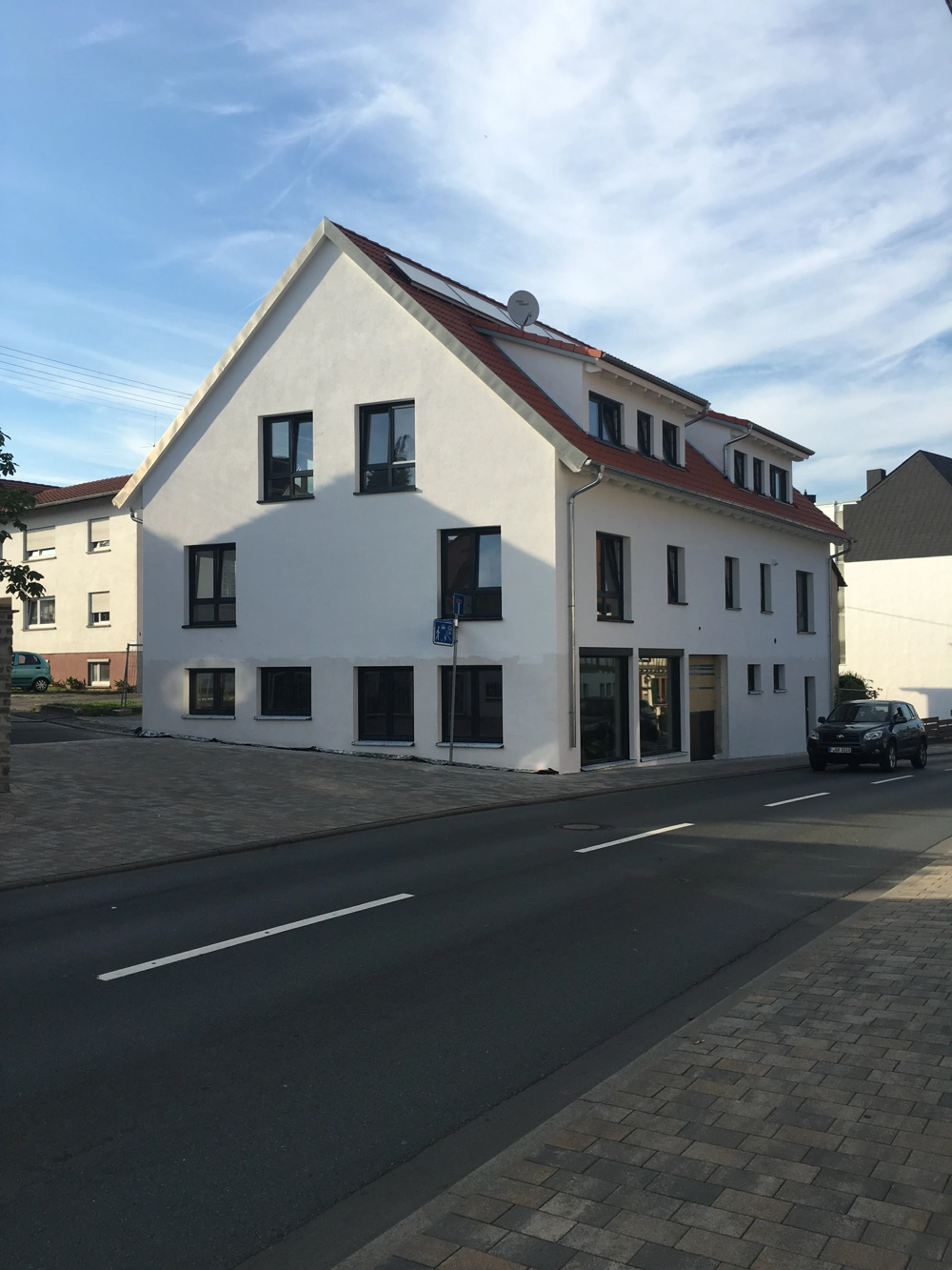 Schlüsselfertiges Neubau-Wohnhaus in Weiß mit glatter Putzfassade, Fensterreihen und rotem Satteldach