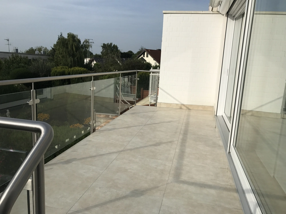 Balkon mit hellen Bodenfliesen und Glasgeländer, Balkon bauen