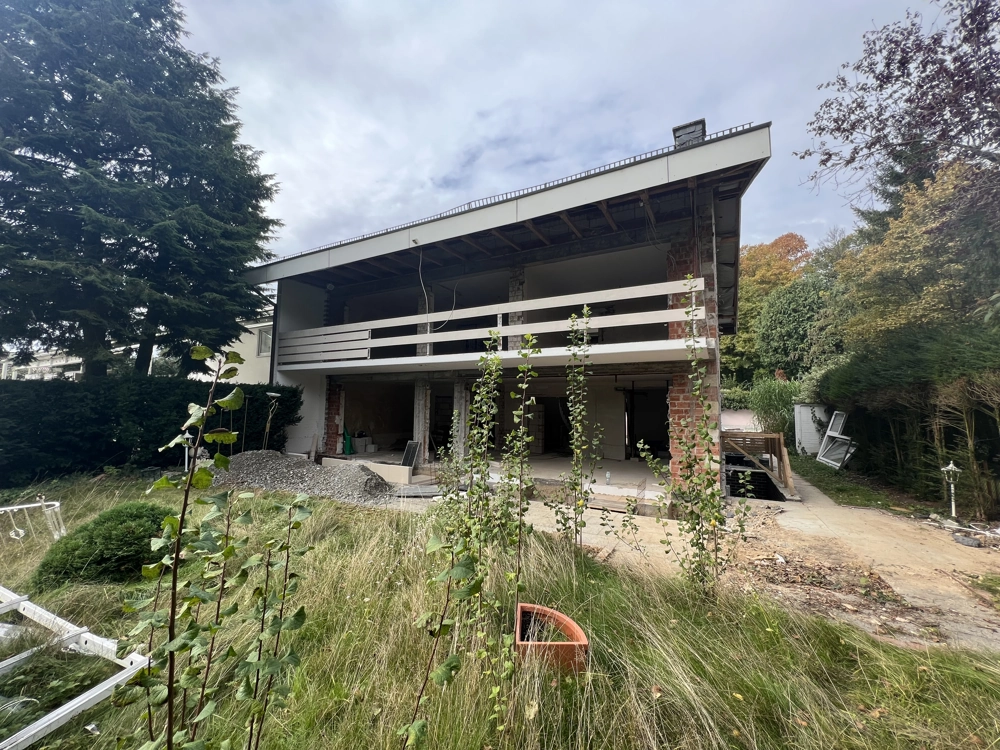 Freigelegte Hausfassade mit Baustellenvorbereitung im Garten für Fassadensanierung