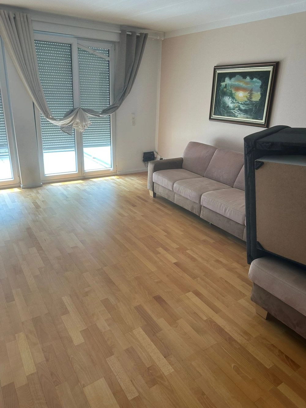 Heller Wohnraum mit neu verlegtem Parkettboden, grauem Sofa, Bild an Wand und großen Fensterfronten, Parkett verlegen