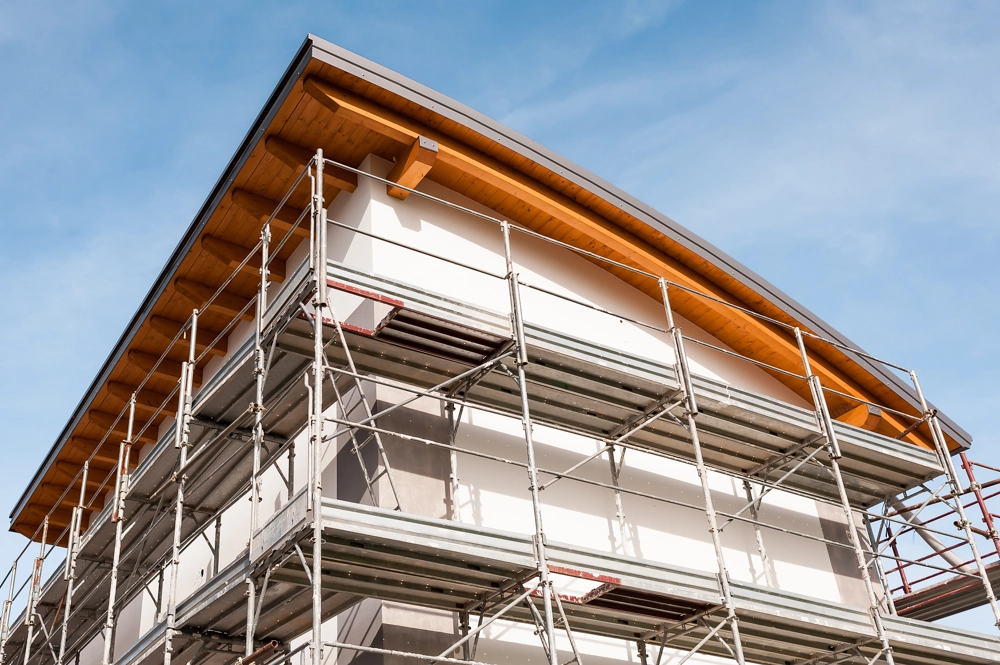 Mehrstöckiges Wohngebäude mit Gerüst und unvollendeter Fassade beim Fassadenbau