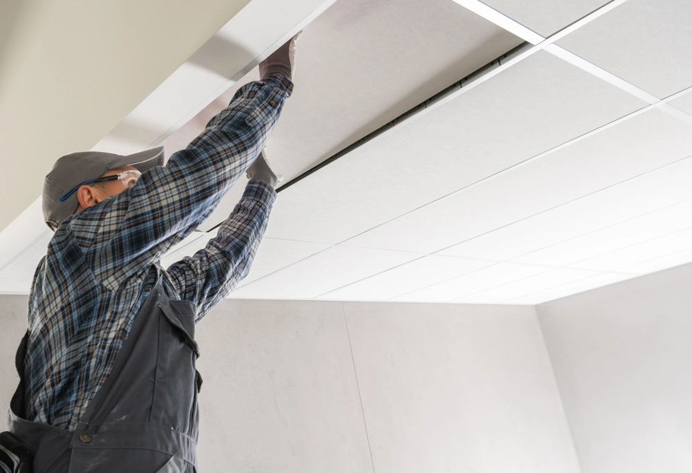 Handwerker montiert Trockenbauplatten im Rahmen von Decke abhängen in modernem Innenraum