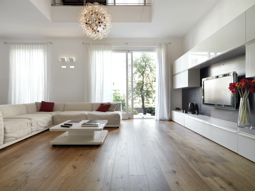 Helles Wohnzimmer mit weißem Ecksofa, Holzparkett, großem Fenster und Wandregalen für Wohnraumgestaltung